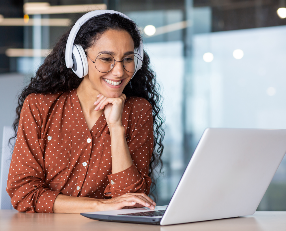 A woman sitting alone with a laptop, focused and engaged, representing dedication to personal growth and continuous learning.